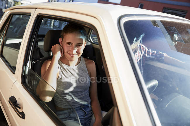 Portrait de jeune femme souriante regardant par la fenêtre de la voiture et l'homme assis dans la voiture — Photo de stock