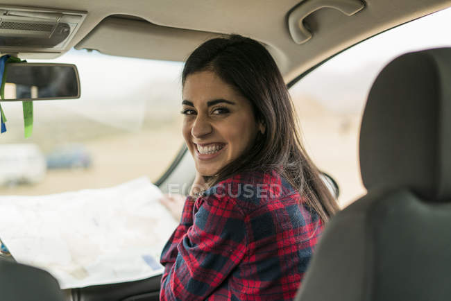 Woman sitting with map in car — Stock Photo