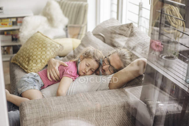 Отец отдыхает с дочерью на диване дома — стоковое фото