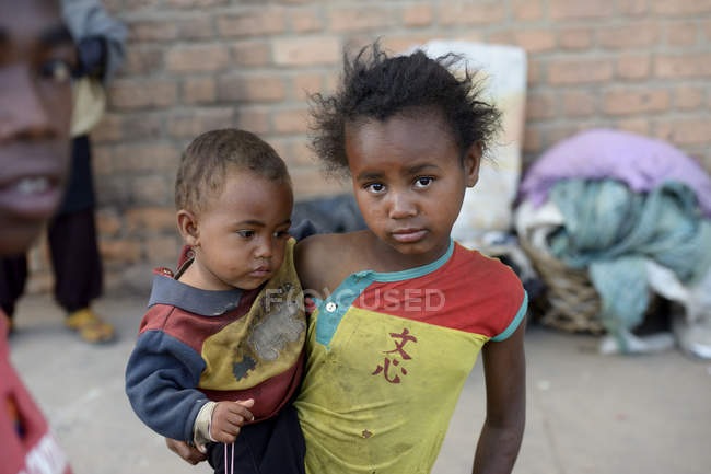 Madagascar, Fianarantsoa, Niña sin hogar llevando a Todler - foto de stock