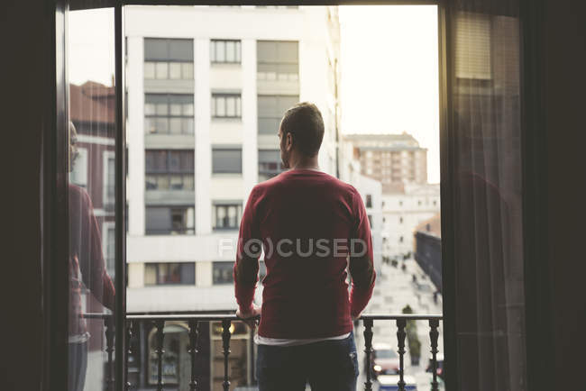 Uomo in piedi su un balcone della città al tramonto — Foto stock