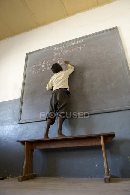 Madagascar, Fianarantsoa, Schoolboy writing on blackboard in elementary school — Stock Photo