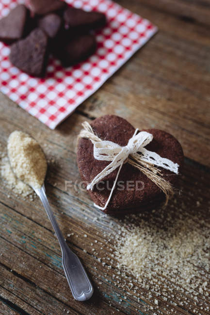 Homemade heart-shaped chocolate cookies tied with ribbon on wood — Stock Photo