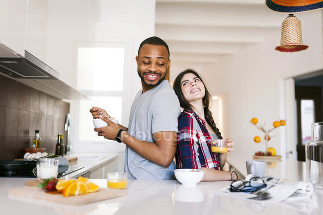 Ritratto di giovane coppia in piedi back to back in cucina — Foto stock
