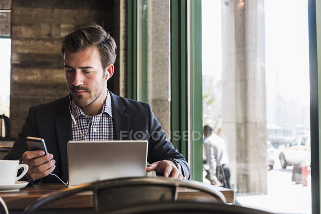 Geschäftsmann mit Tablet und Handy im Café — Stockfoto