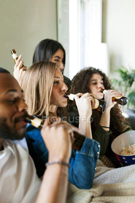 Ritratto copped di giovani amici beventi sul divano — Foto stock