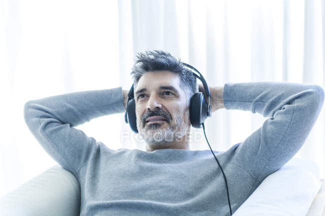 Porträt eines reifen Mannes, der Musik auf dem Sofa hört — Stockfoto