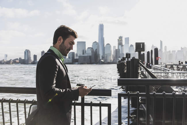 USA, New York, ponte di Brooklyn, Giovane con smartphone, paesaggio urbano sullo sfondo — Foto stock