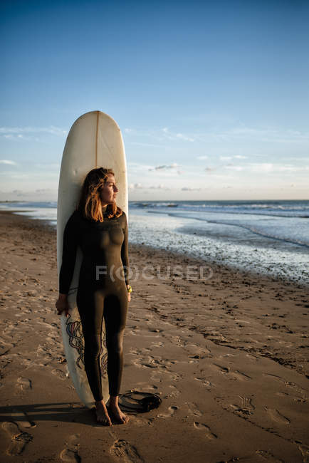 Female surfer with board on the shore at sunset — Stock Photo