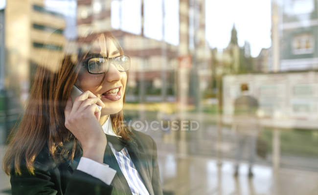 Geschäftsfrau telefoniert vor Glasscheibe — Stockfoto