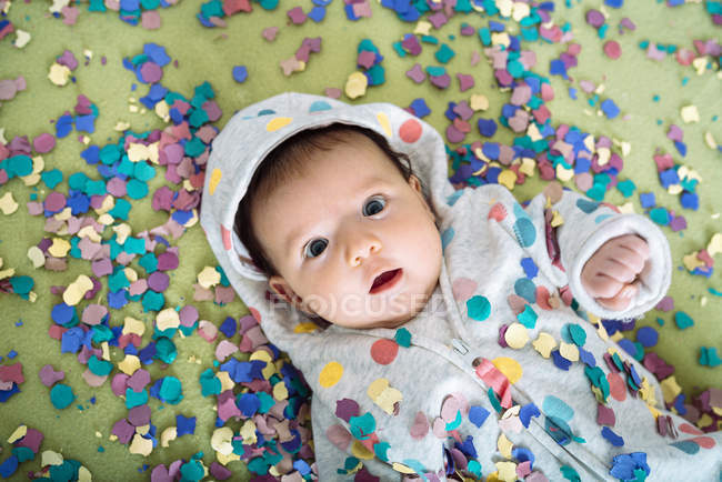 Bambina stupita circondata da coriandoli colorati — Foto stock