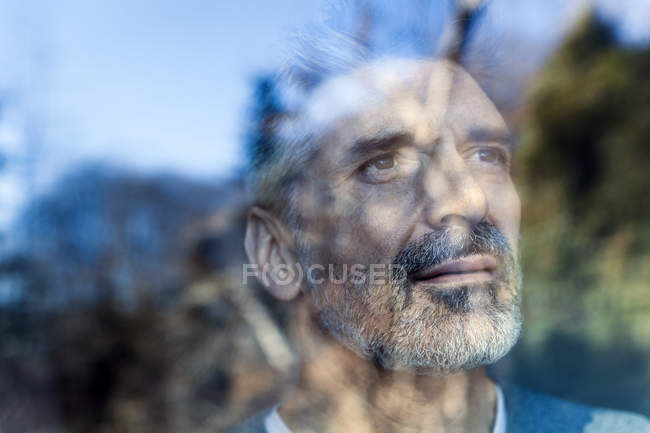 Retrato del hombre maduro mirando a través del cristal de la ventana - foto de stock