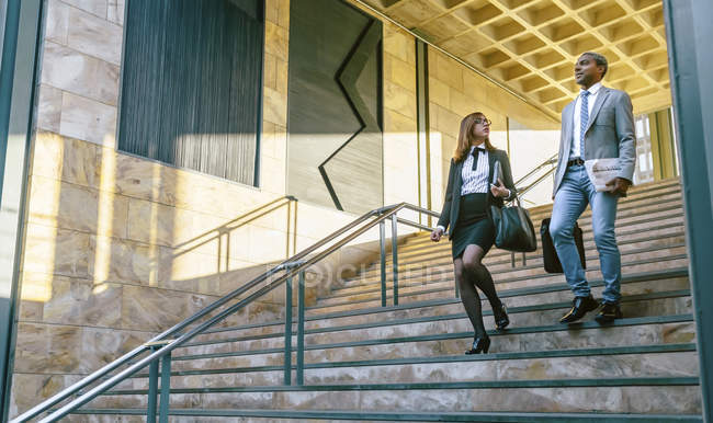 Young businessman and businesswoman walking downstairs — Stock Photo