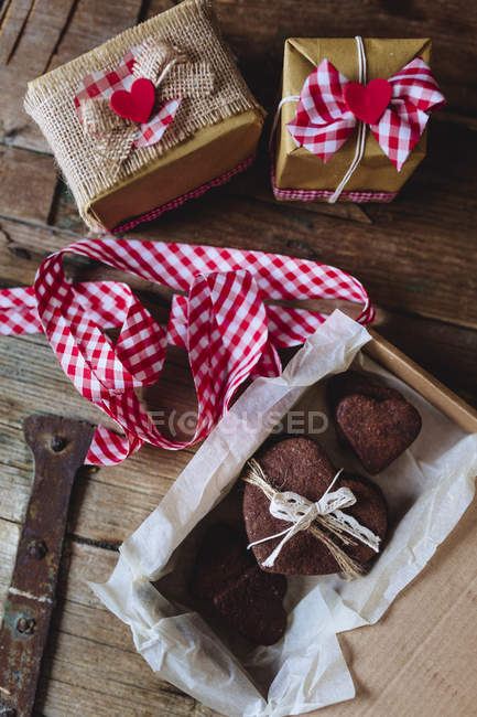 Biscotti al cioccolato fatti in casa a forma di cuore in scatola con scatole regalo su legno — Foto stock