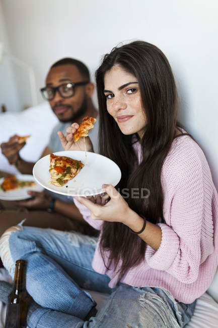 Ritratto di una giovane coppia che mangia pizza sul letto — Foto stock