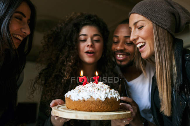 Ritratto ritagliato di giovani amici che guardano la torta di compleanno con candele accese — Foto stock
