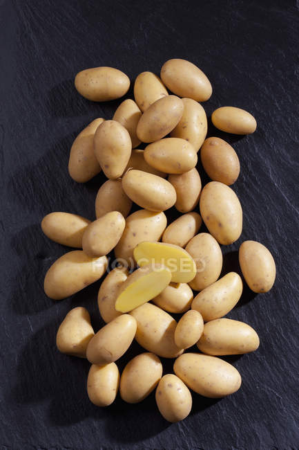 Vue surélevée de pommes de terre entières et coupées sur fond noir — Photo de stock