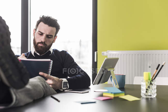 Porträt eines jungen Geschäftsmannes mit Notizbuch am Tisch — Stockfoto