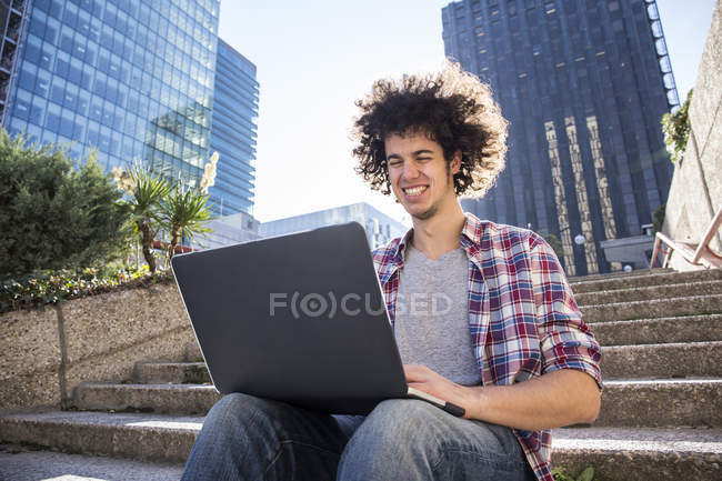 Молода людина, сидячи на сходах і використання ноутбука — стокове фото