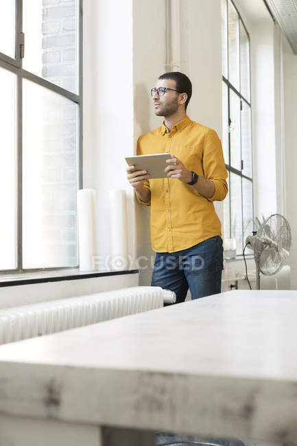 Jeune homme d'affaires tenant une tablette numérique au bureau — Photo de stock