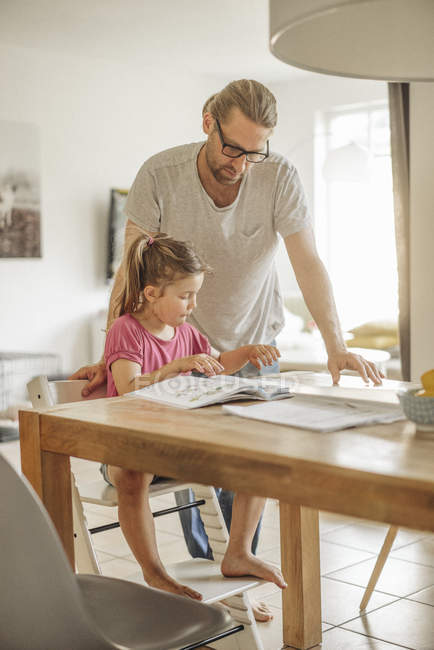 Father checking homework of daughter at home — Stock Photo