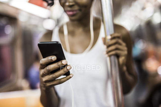 Freigeschnittenes Porträt einer Frau mit Smartphone in U-Bahn — Stockfoto