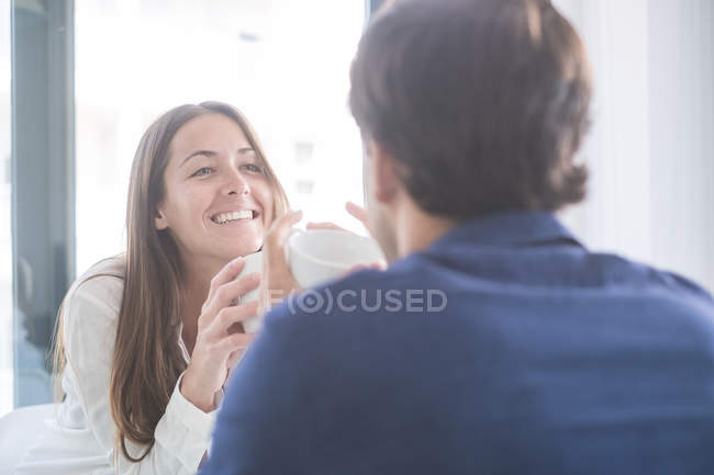 Couple with coffee cups looking one at other — Stock Photo