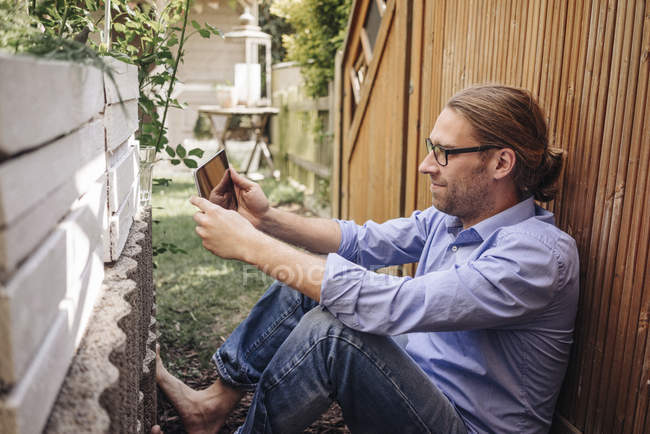 Man relaxing in garden and using digital tablet — Stock Photo