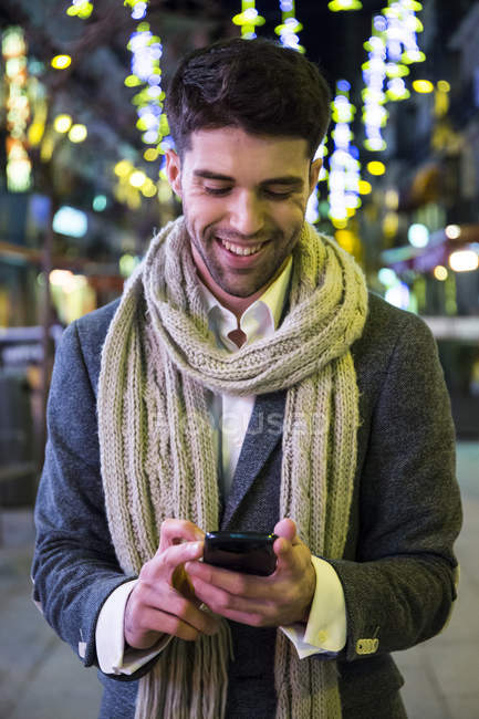 Человек, использующий свой мобильный телефон в городе ночью — стоковое фото