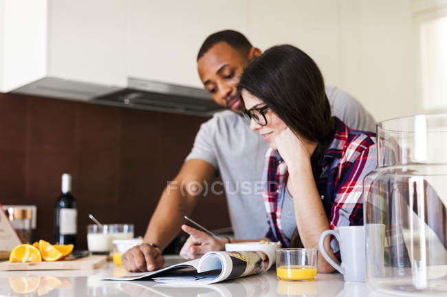 Ritratto di una giovane coppia che guarda la rivista in cucina — Foto stock
