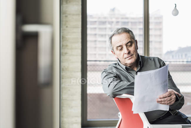 Porträt eines leitenden Geschäftsmannes beim Betrachten von Dokumenten — Stockfoto