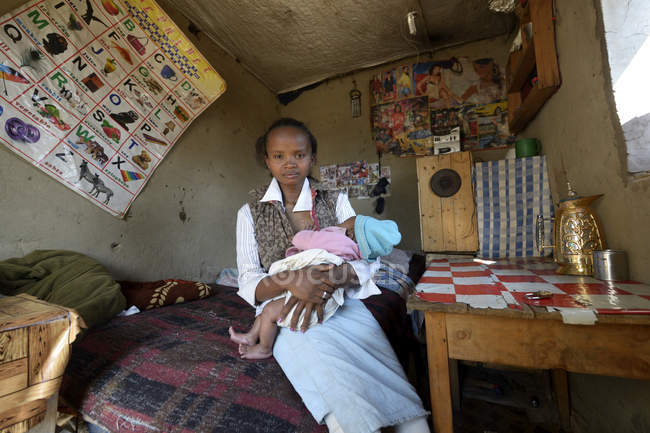 Madagáscar, Fianarantsoa, Jovem mãe segurando bebê em quarto pobre — Fotografia de Stock