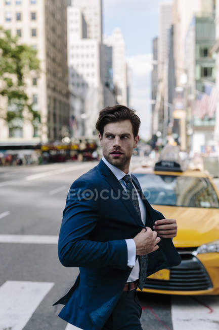 Retrato de hombre de negocios cruzando la calle y mirando a un lado - foto de stock