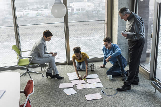 Retrato de colegas de negocios ordenando documentos en el piso - foto de stock