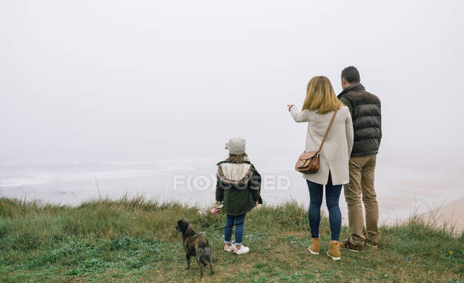 Back view of family looking the beach in a foggy day on winter — Stock Photo