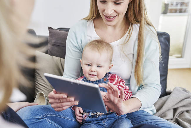Mãe e bebê menina em casa olhando para tablet — Fotografia de Stock
