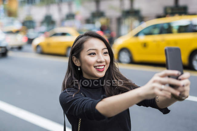 Portrait of young woman taking selfie at street — Stock Photo