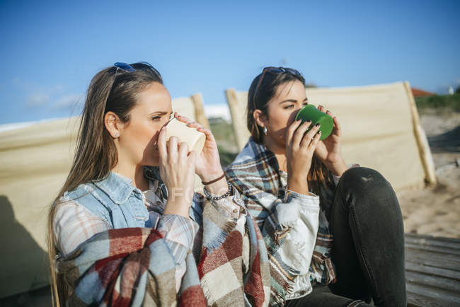 Due giovani donne che bevono da tazze di metallo sulla spiaggia in Spagna, Andalusia, Vejer de la Frontera — Foto stock
