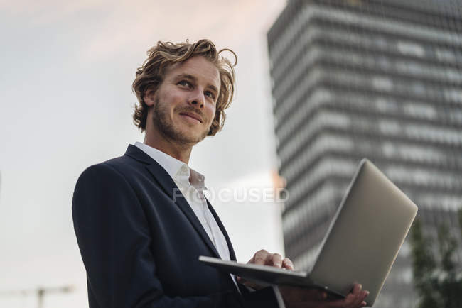 Geschäftsmann nutzt Laptop im Freien und schaut zur Seite — Stockfoto