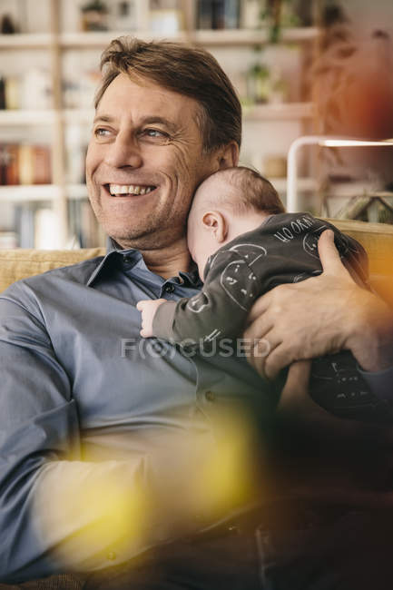Happy father with newborn baby sitting on couch at home — Stock Photo