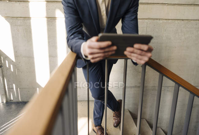 Обрезанный портрет бизнесмена, держащего планшет на лестнице — стоковое фото