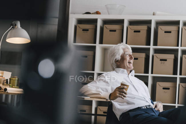 Portrait of smiling senior businessman sitting in office — Stock Photo