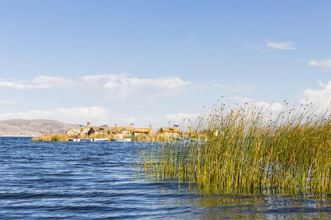 Vista del lago con hierba y edificios en el fondo durante el día, perú - foto de stock