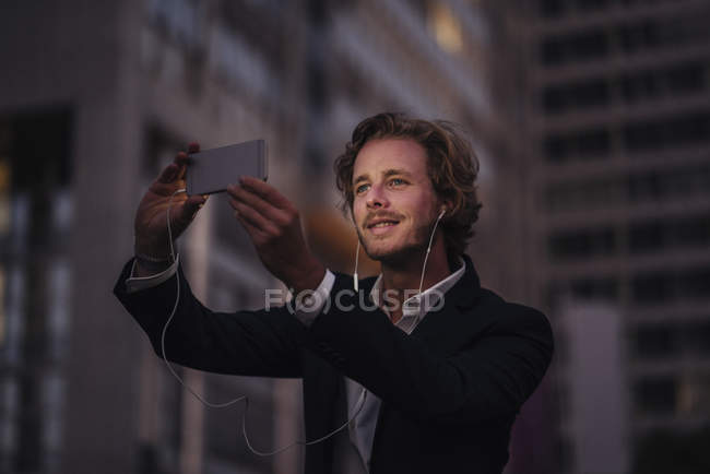 Бизнесмен в городе в сумерках с помощью мобильного телефона — стоковое фото