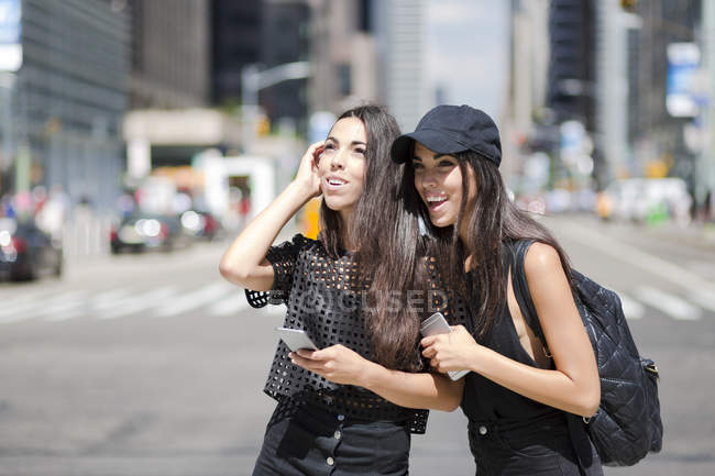 Twin sisters with cell phones in city — Stock Photo