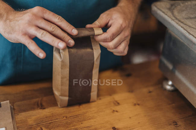Close-up of man packing bag of coffee at shop counter — Stock Photo
