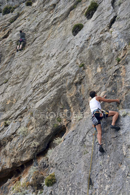 Ritratto posteriore diurno di due uomini che si arrampicano sulla parete rocciosa — Foto stock