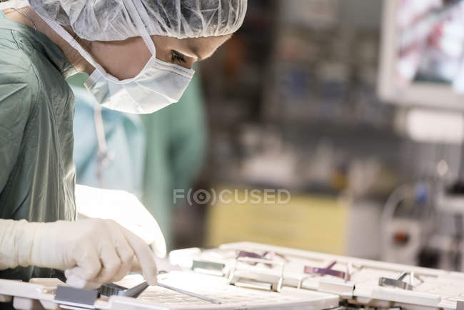 Enfermeira da sala cirúrgica à procura de um instrumento — Fotografia de Stock