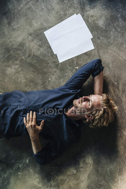 Cher homme couché sur le sol à côté de papiers — Photo de stock