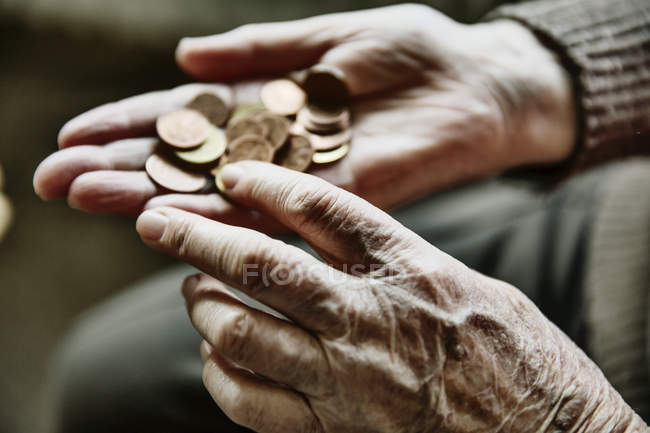 Руки пожилой женщины с монетами — стоковое фото